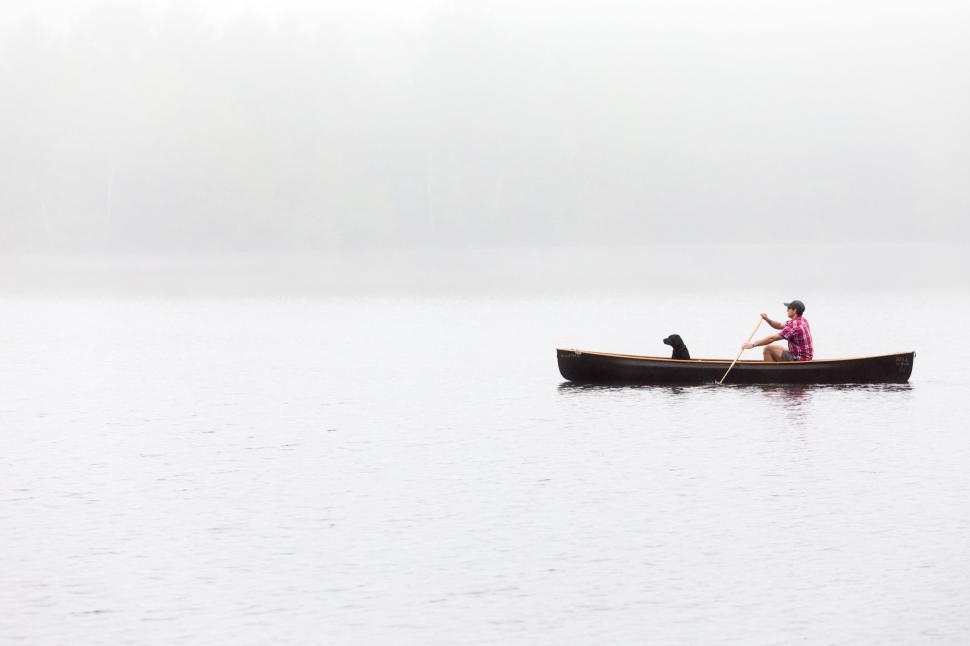 Free Image of Person paddling canoe with dog in fog-covered lake 
