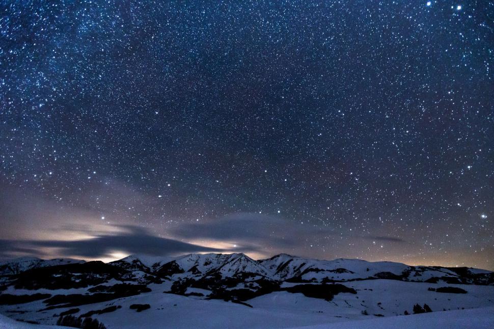 Free Image of Starry night sky over snow-covered mountain landscape 