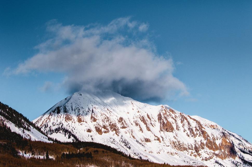 Free Image of Snow-capped mountain peak shrouded partially by clouds. 