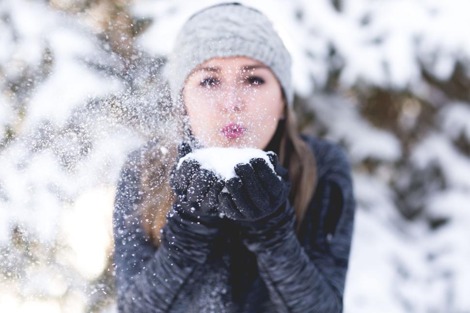 Free Image of Woman enjoying the snow, blowing it in winter wonderland 