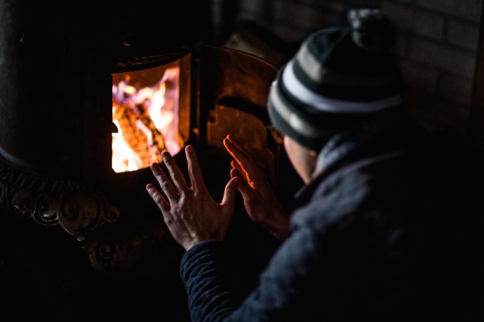 Free Image of Person warming hands by the fire in a cozy setting. 