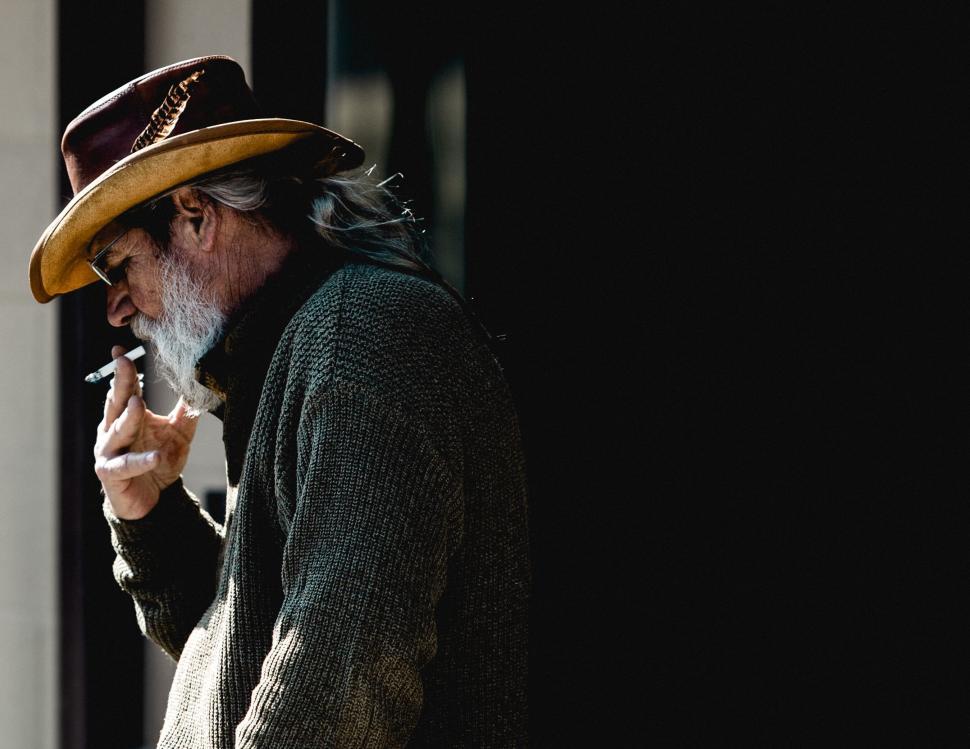 Free Image of Man wearing cowboy hat with black background smoking 