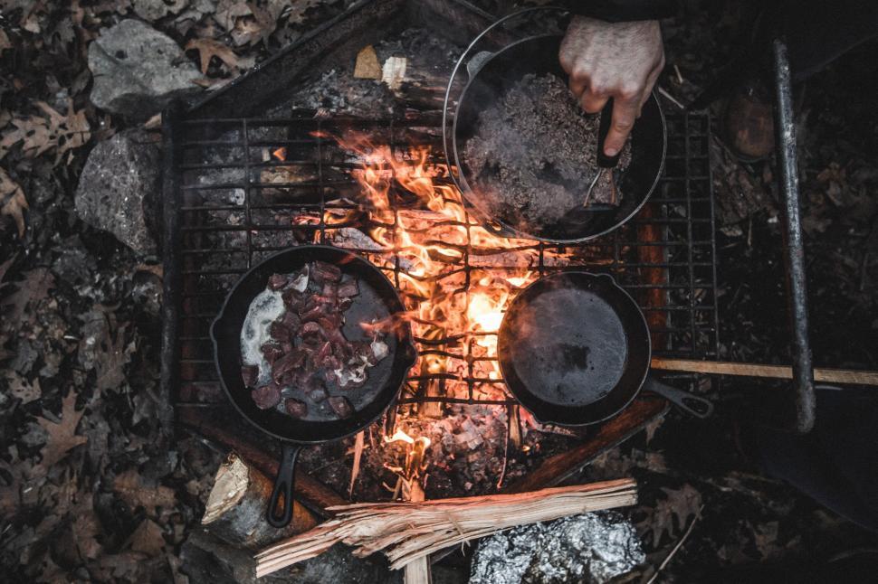 Free Image of Person cooking food over an open campfire in the woods 