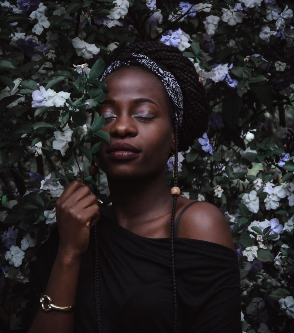 Free Image of Woman with eyes closed surrounded by floral foliage. 