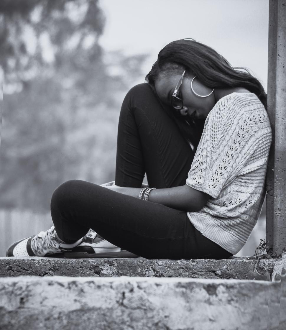 Free Image of Person sitting alone with head on knees by the wall 