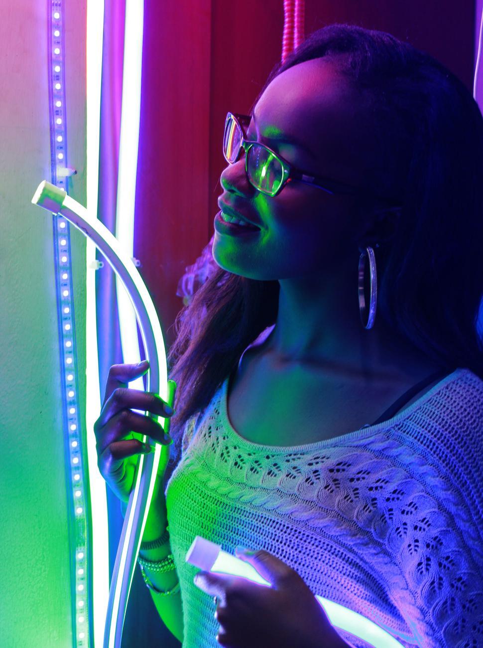 Free Image of Woman holding neon lights in a colorful environment. 