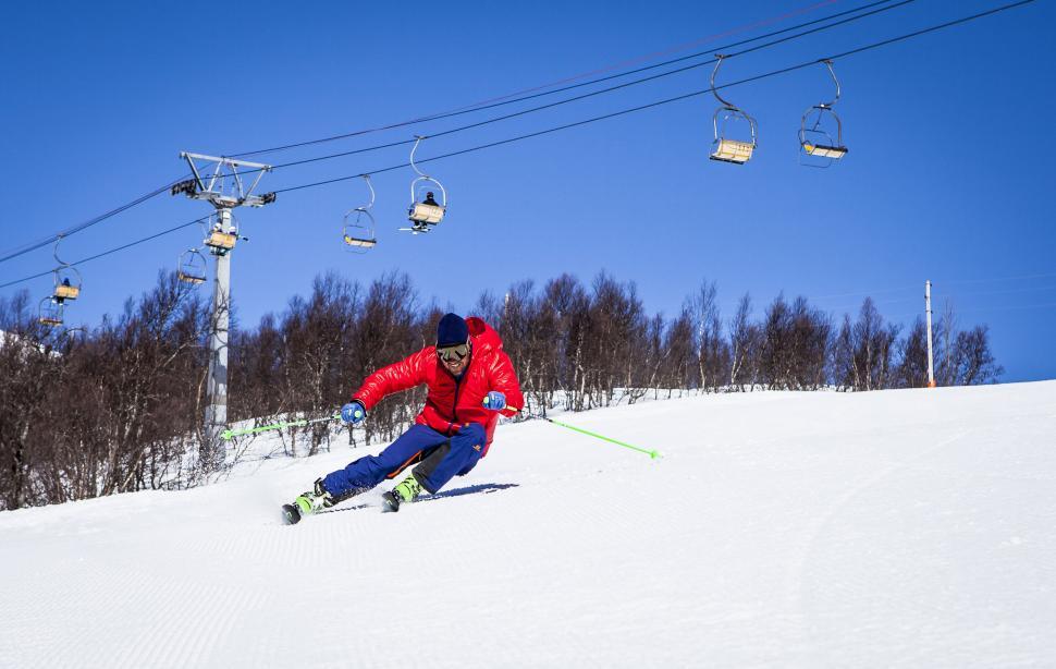 Free Image of Skier performing a wide turn on a snow-covered hill. 