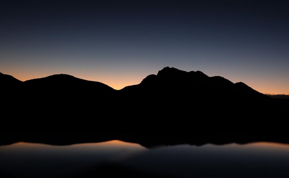 Free Image of Silhouette of mountains against a twilight sky reflection 