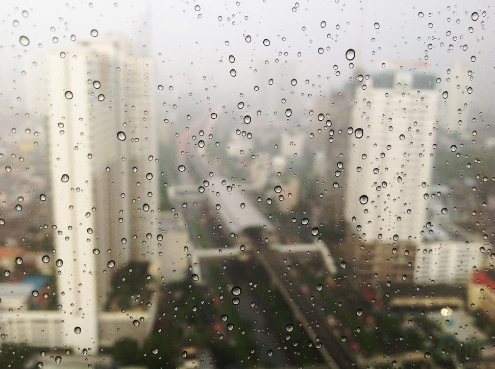 Free Image of Cityscape view through a rainy window with water droplets 