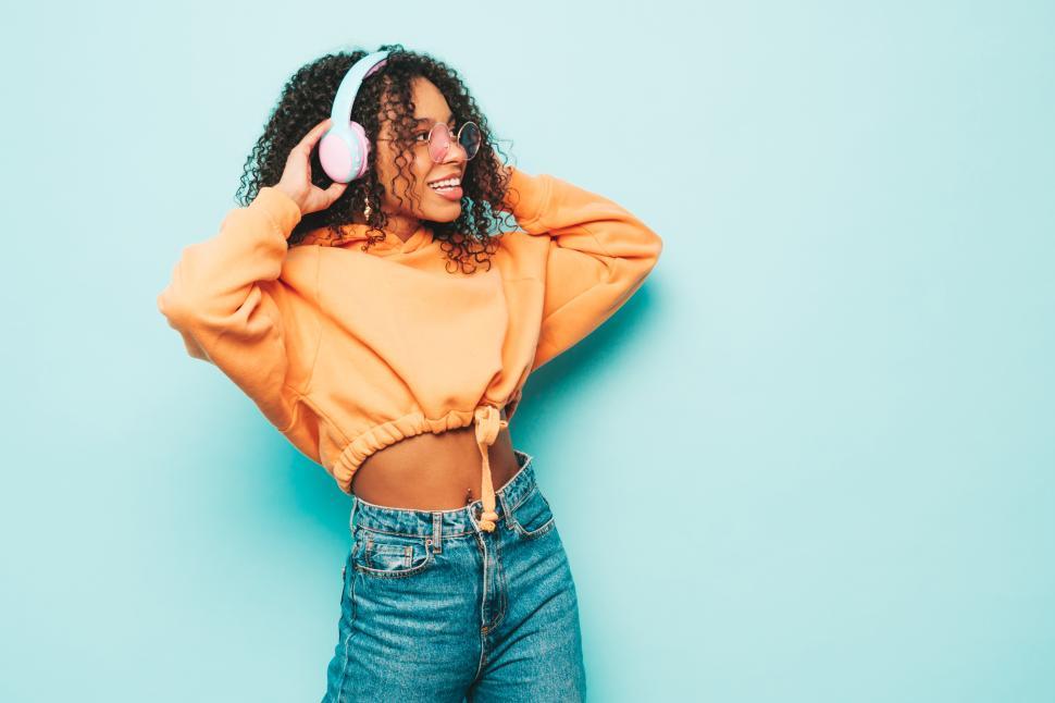 Free Image of Woman with headphones, stylish orange top, joyful mood 