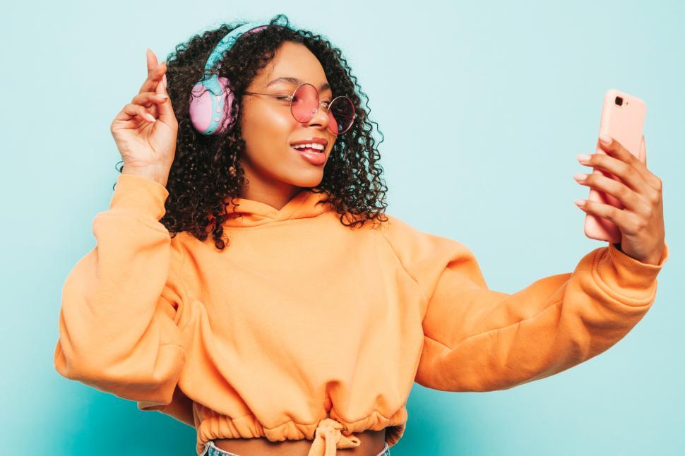 Free Image of Joyful woman taking selfie wearing orange top, indoors 