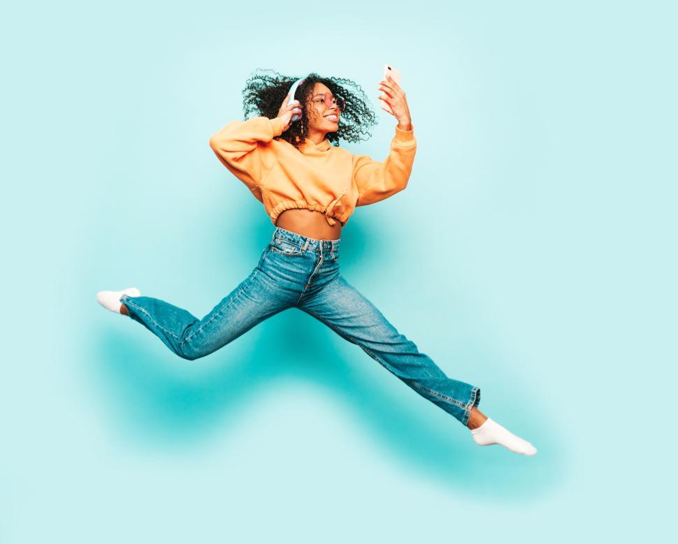 Free Image of Woman jumping energetically while taking a selfie. 