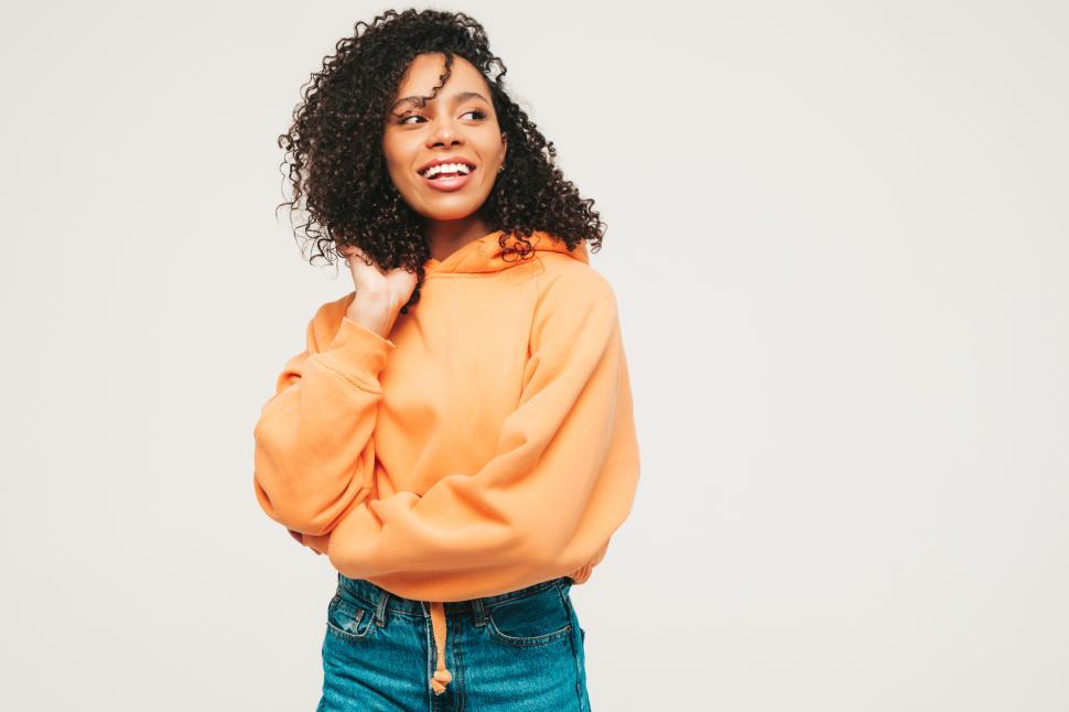 Free Image of Smiling woman in orange hoodie posing confidently. 