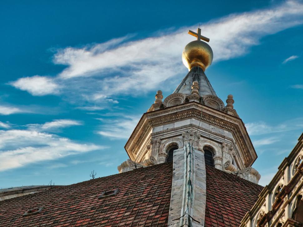 Free Image of Ornate church spire with golden cross under blue sky. 