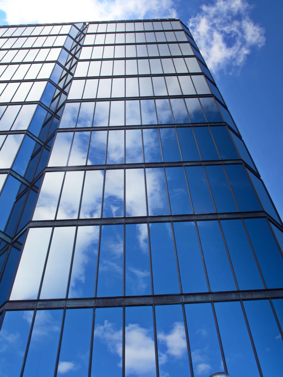 Free Image of Blue glass building reflecting clear sky and clouds 