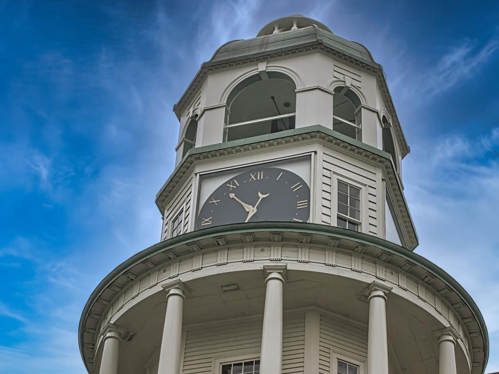 Free Image of Historical clock tower with Roman numerals under blue sky 