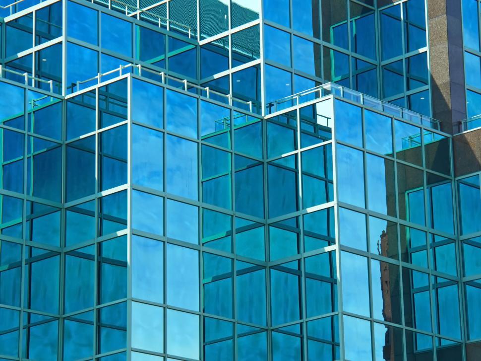 Free Image of Reflective blue glass building facade showing urban sky 