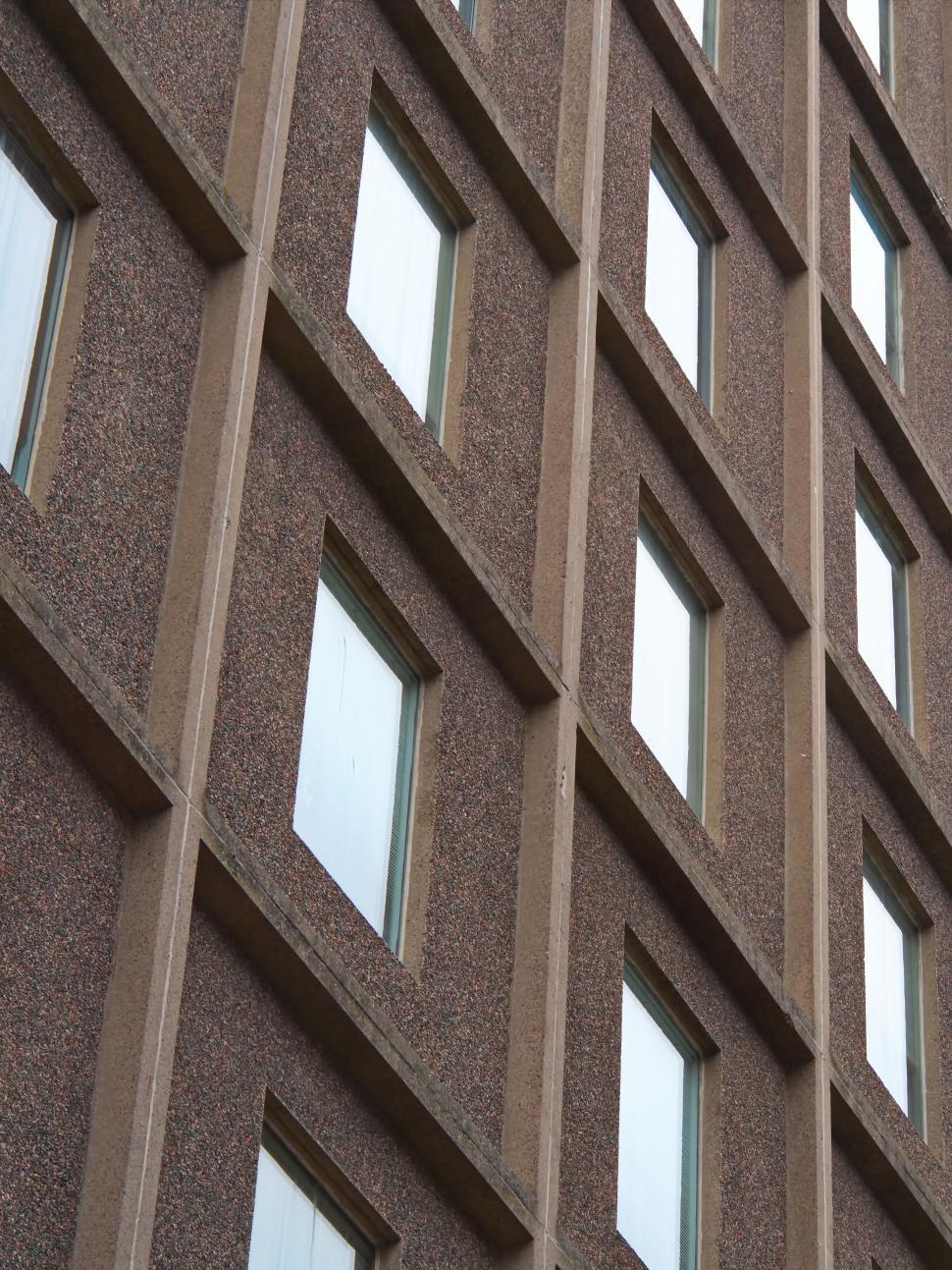 Free Image of Textured brown facade of an apartment building, windows 