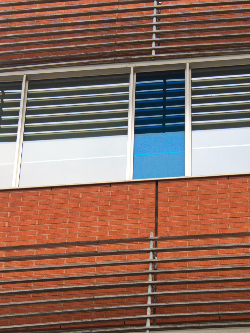 Free Image of Brick facade with unique blue accent window and louvers. 