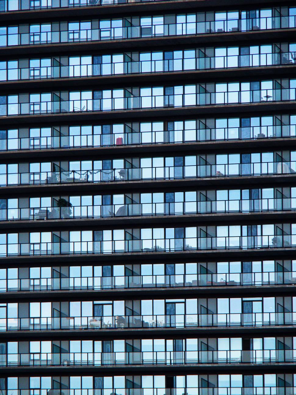 Free Image of Multiple identical windows and balconies on a building facade 