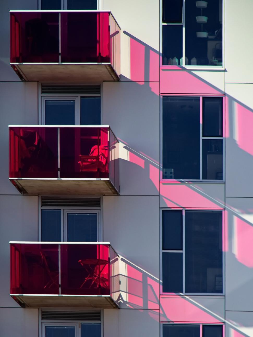 Free Image of Modern building with red balconies and shadow effects 