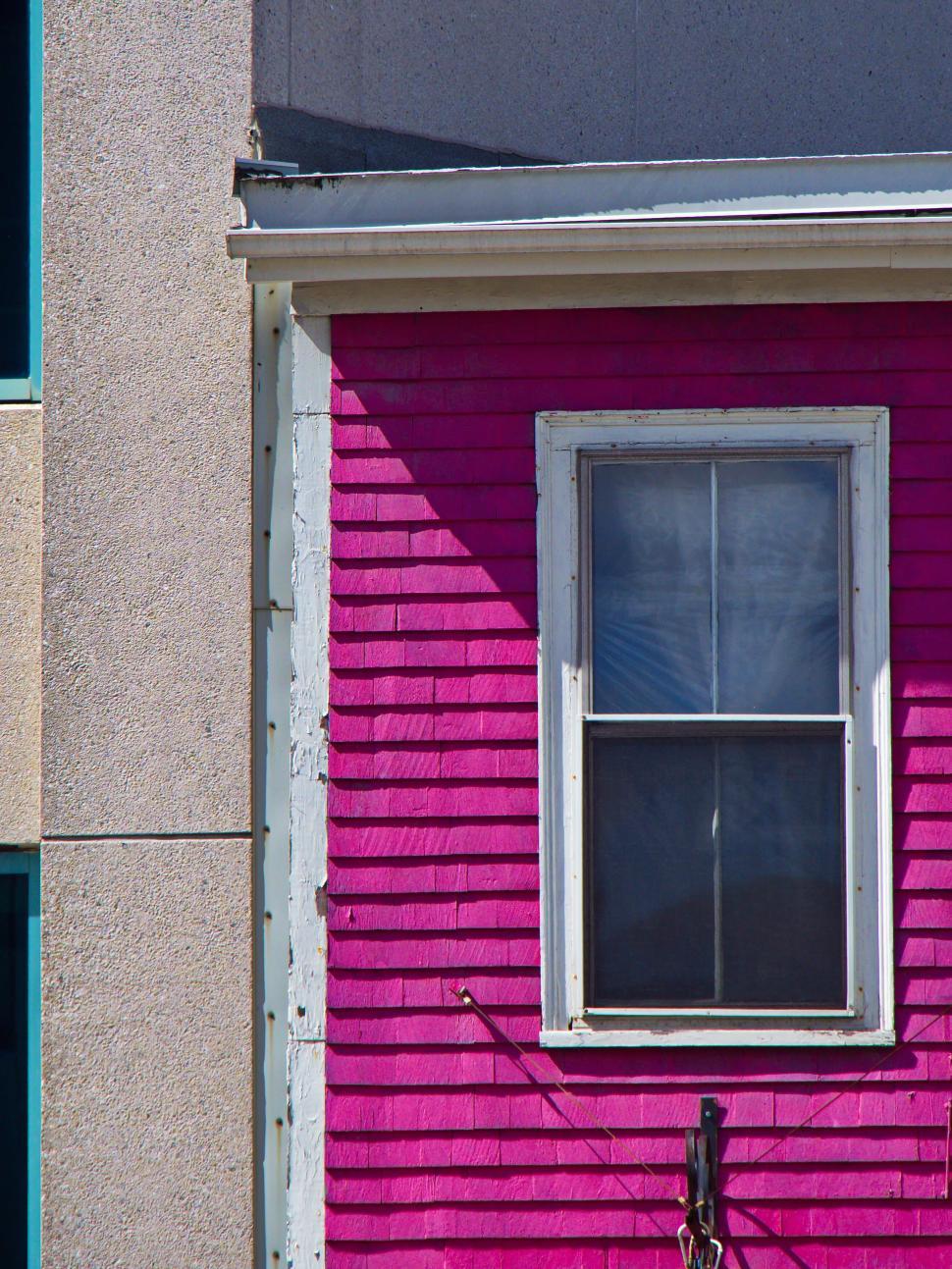 Free Image of Bright pink house section adjacent to concrete wall. 