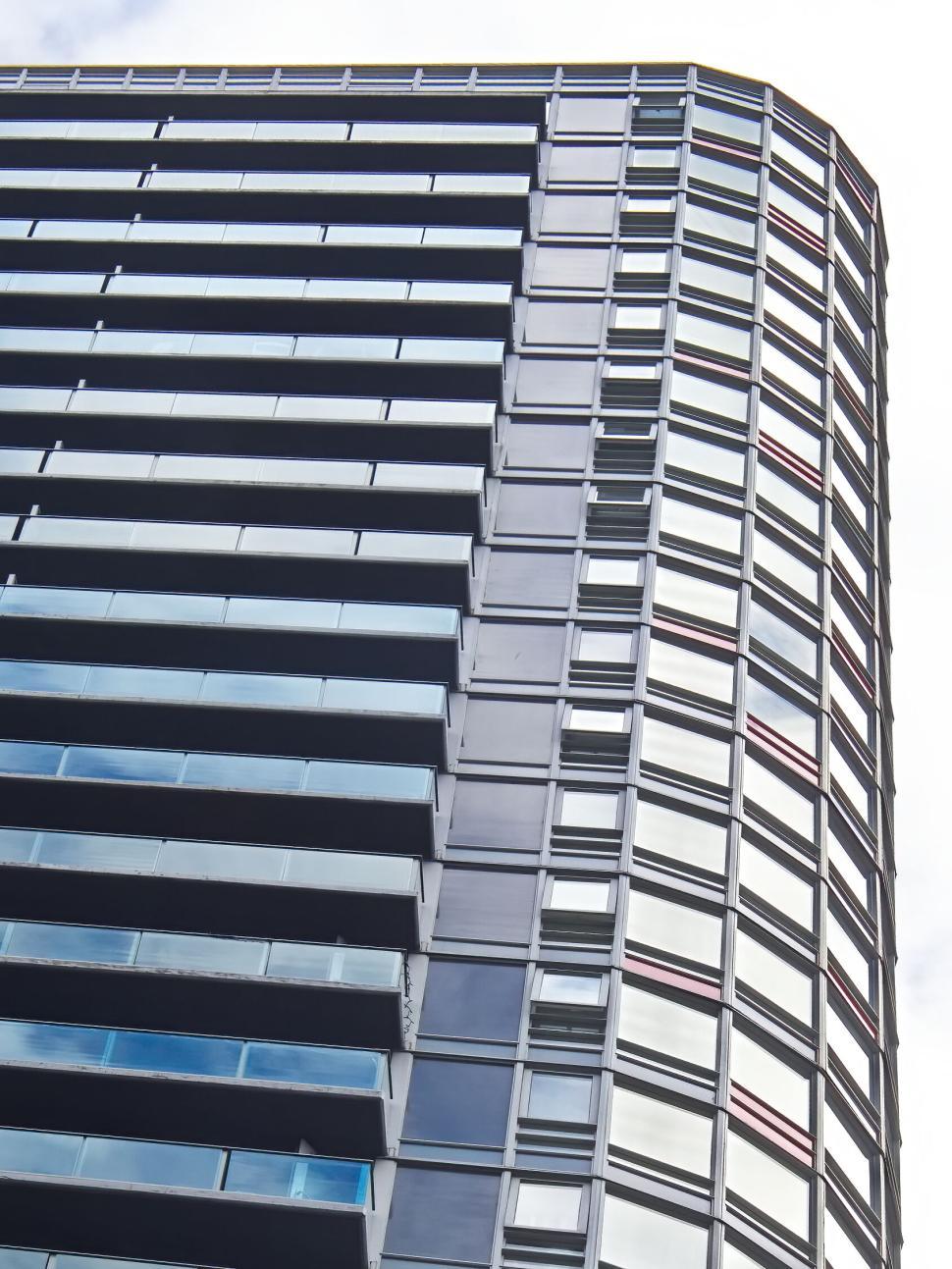 Free Image of Tall curved glass skyscraper reflecting the blue sky. 