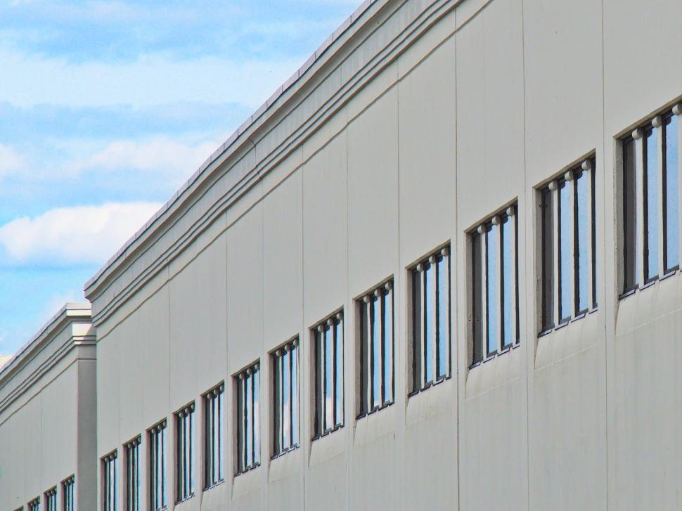 Free Image of Long row of identical windows on beige industrial building. 