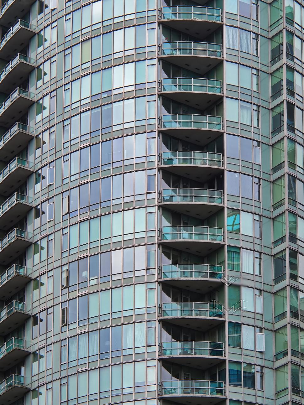 Free Image of Curved glass high-rise building with multiple balconies 