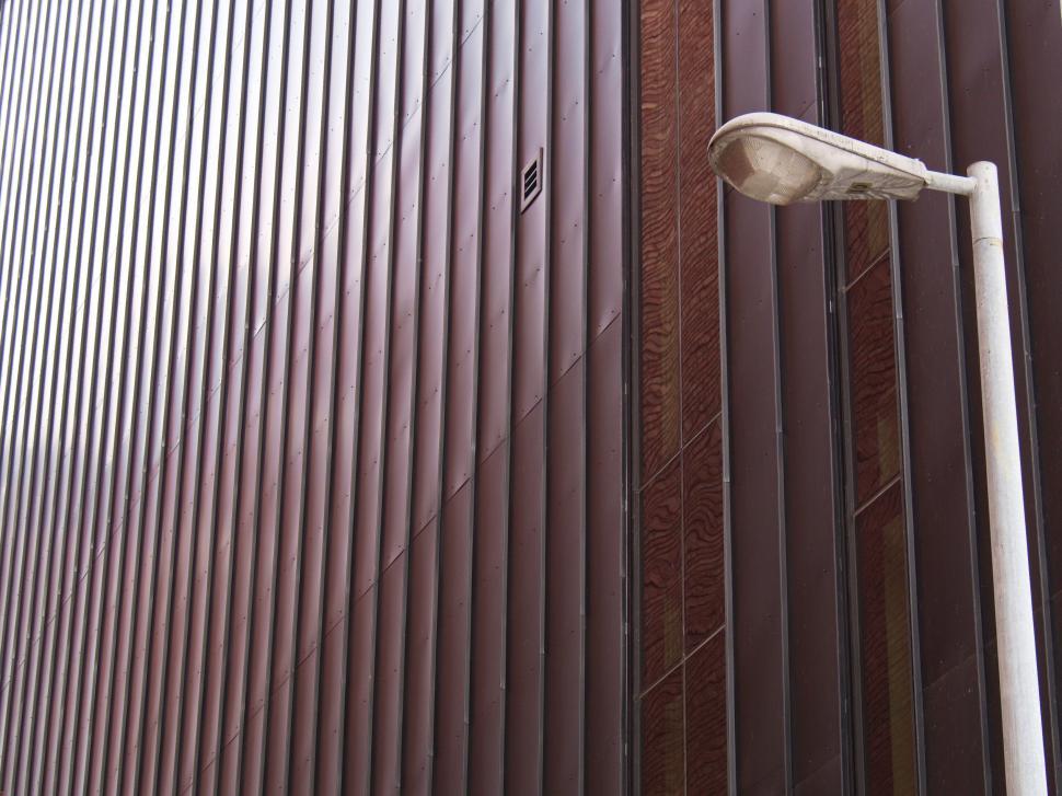 Free Image of Detailed wall with vertical metal designs and street lamp. 