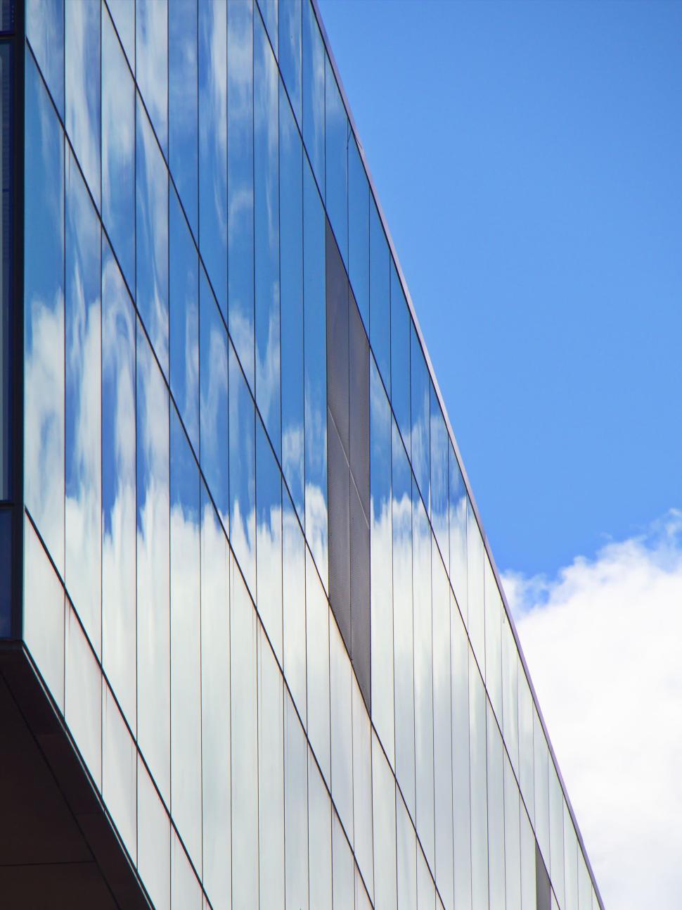 Free Image of Reflective glass building facade with blue sky backdrop. 