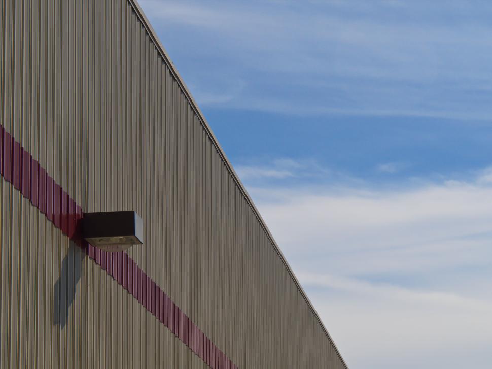 Free Image of Industrial warehouse with metal siding and cloudy sky 