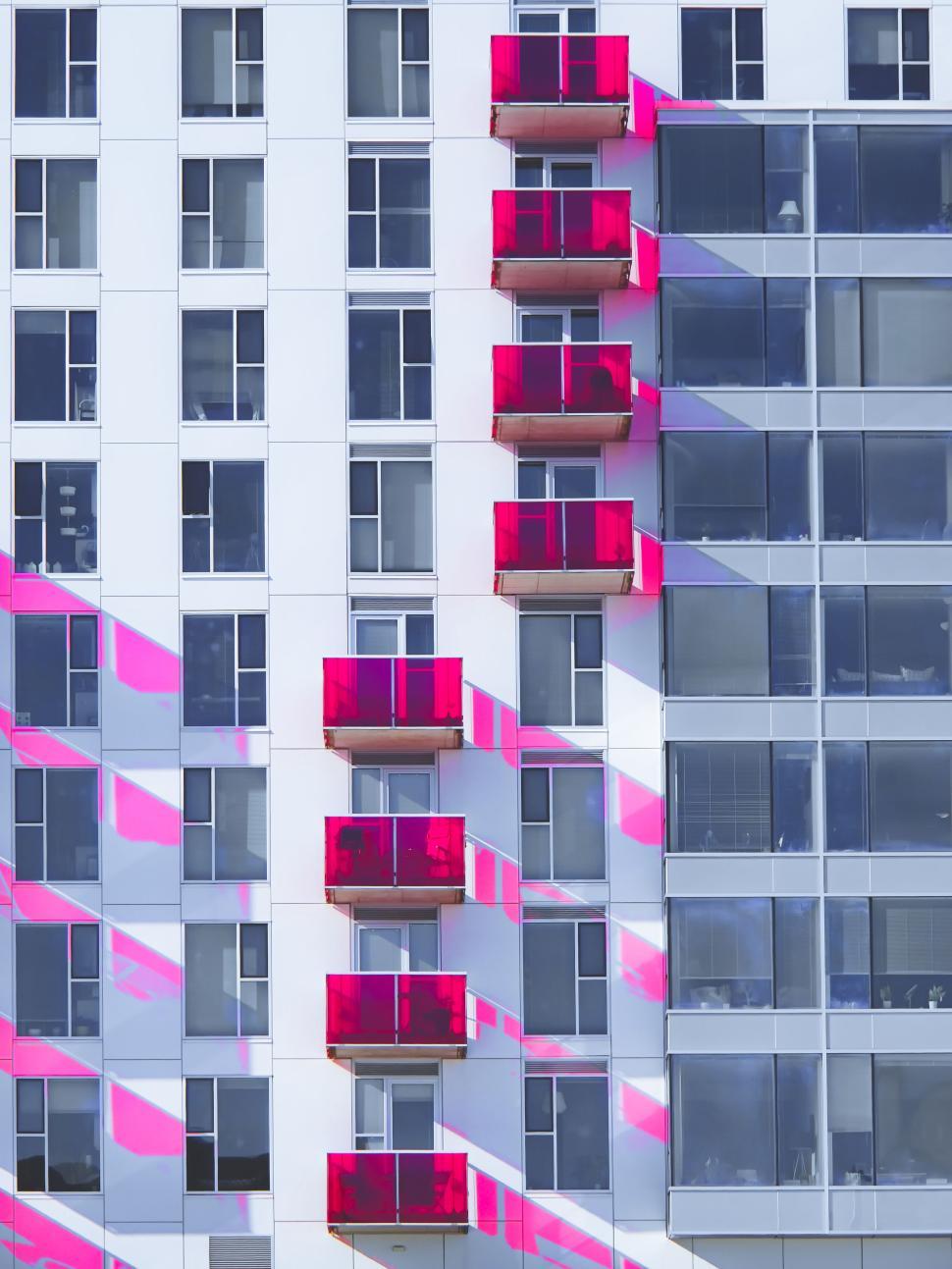 Free Image of Modern building facade with bright pink balconies shown. 