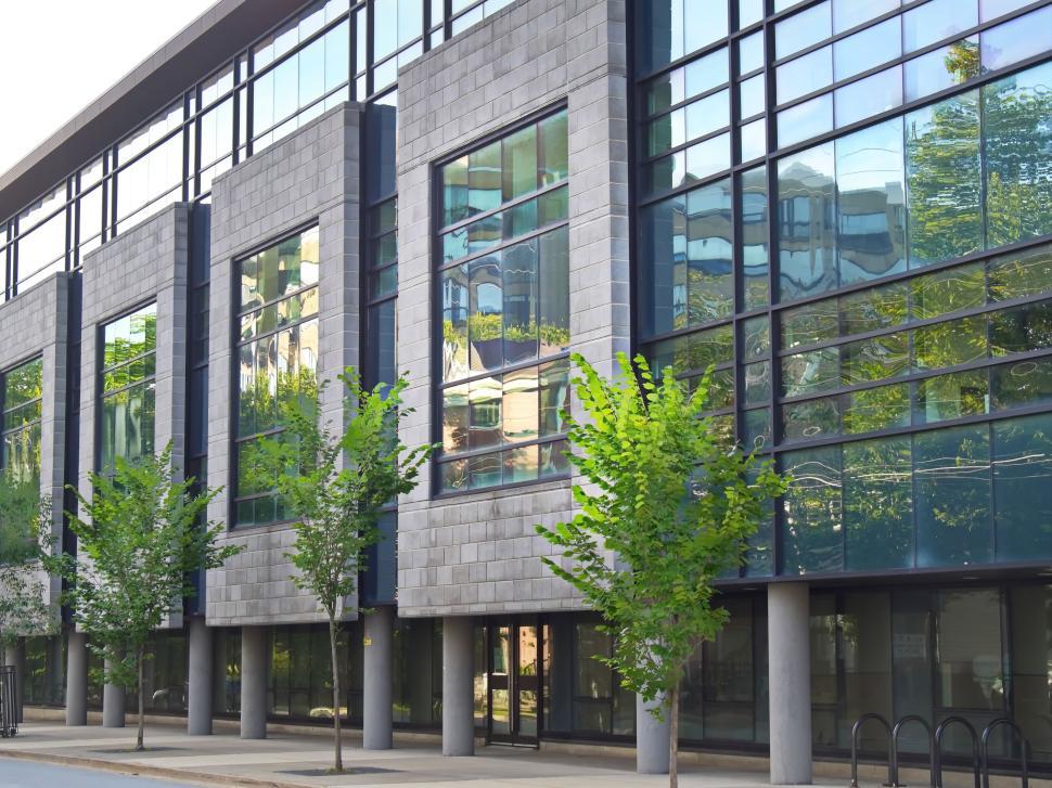 Free Image of Modern building with large windows and young trees outside. 