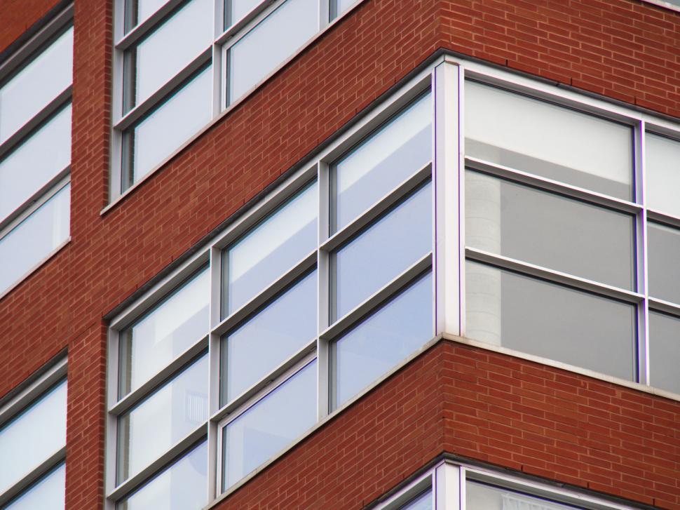 Free Image of Corner of a brick building with modern large windows shown. 
