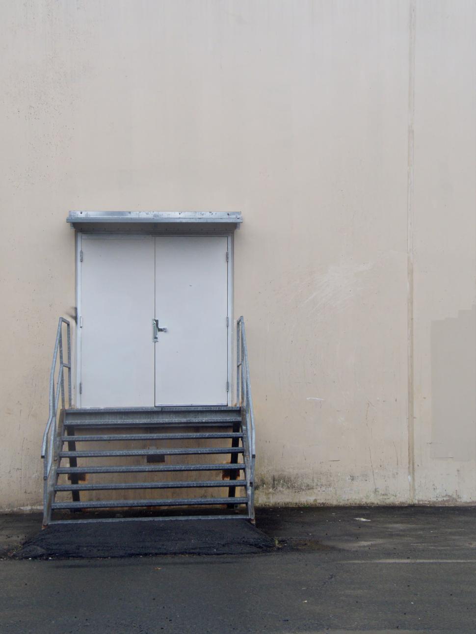 Free Image of Rear access door with stairs on a plain wall exterior. 