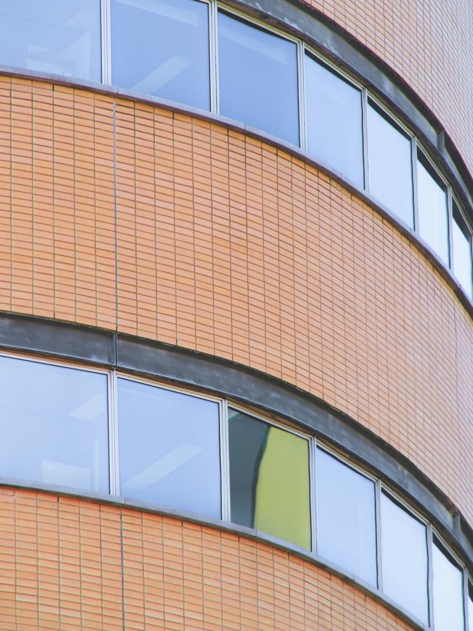 Free Image of Curved brick building with reflective windows facade view. 