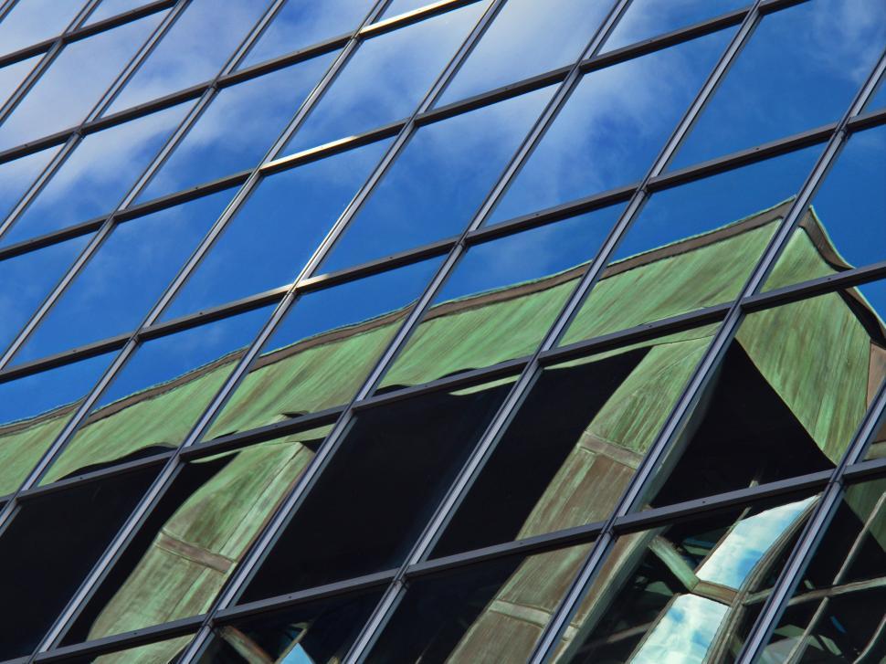 Free Image of Glass Grid Facade Reflecting Blue Sky And Clouds 
