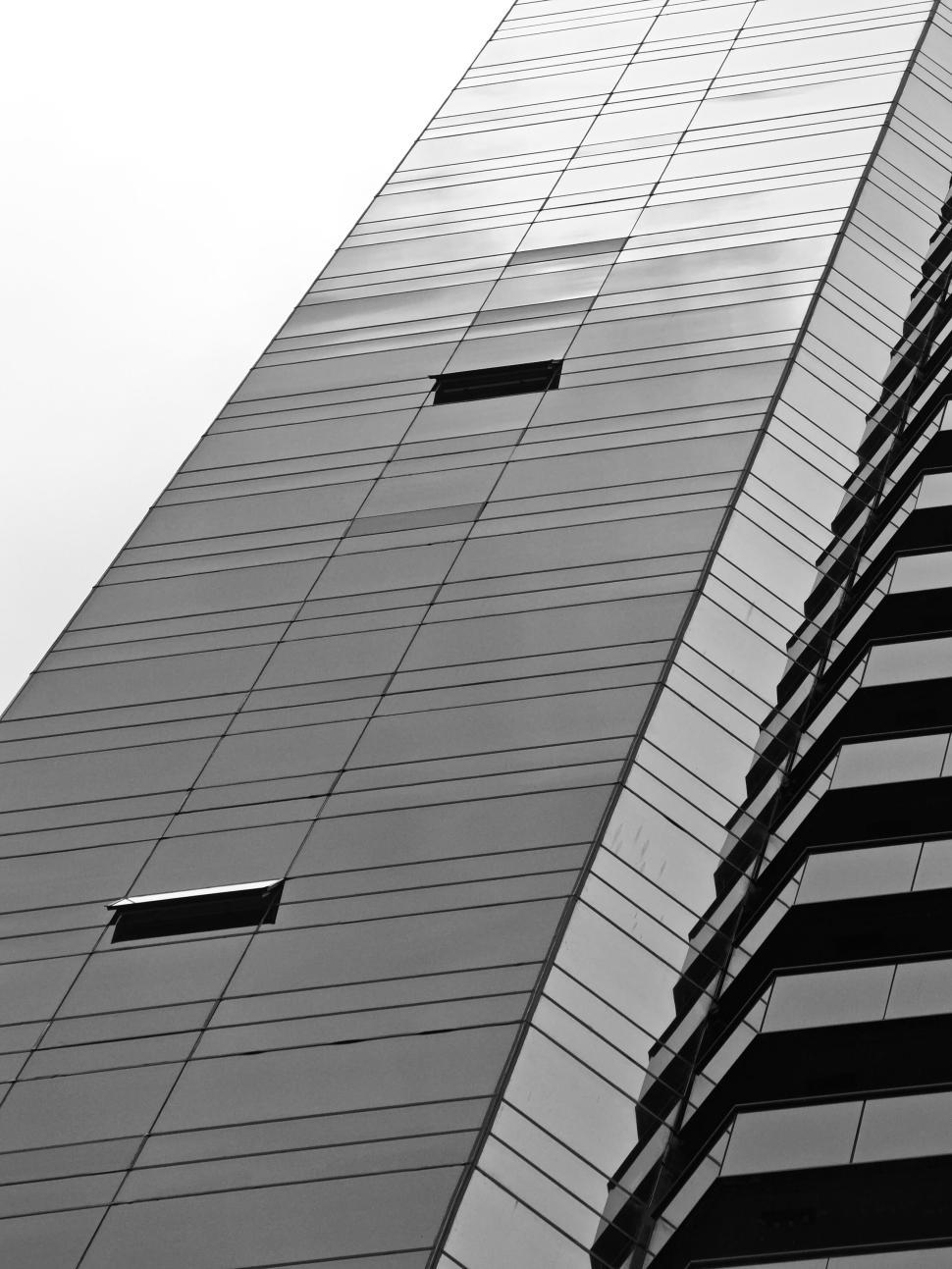 Free Image of Tall mirrored glass skyscraper reflecting the cloudy sky. 