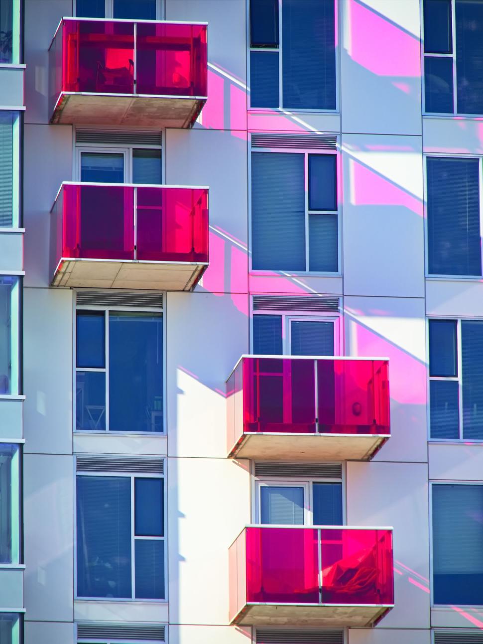 Free Image of Colorful modern building with red glass balconies outside. 