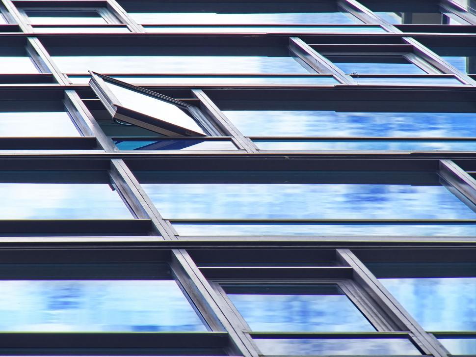 Free Image of Windows on a high-rise building reflecting the sky view. 