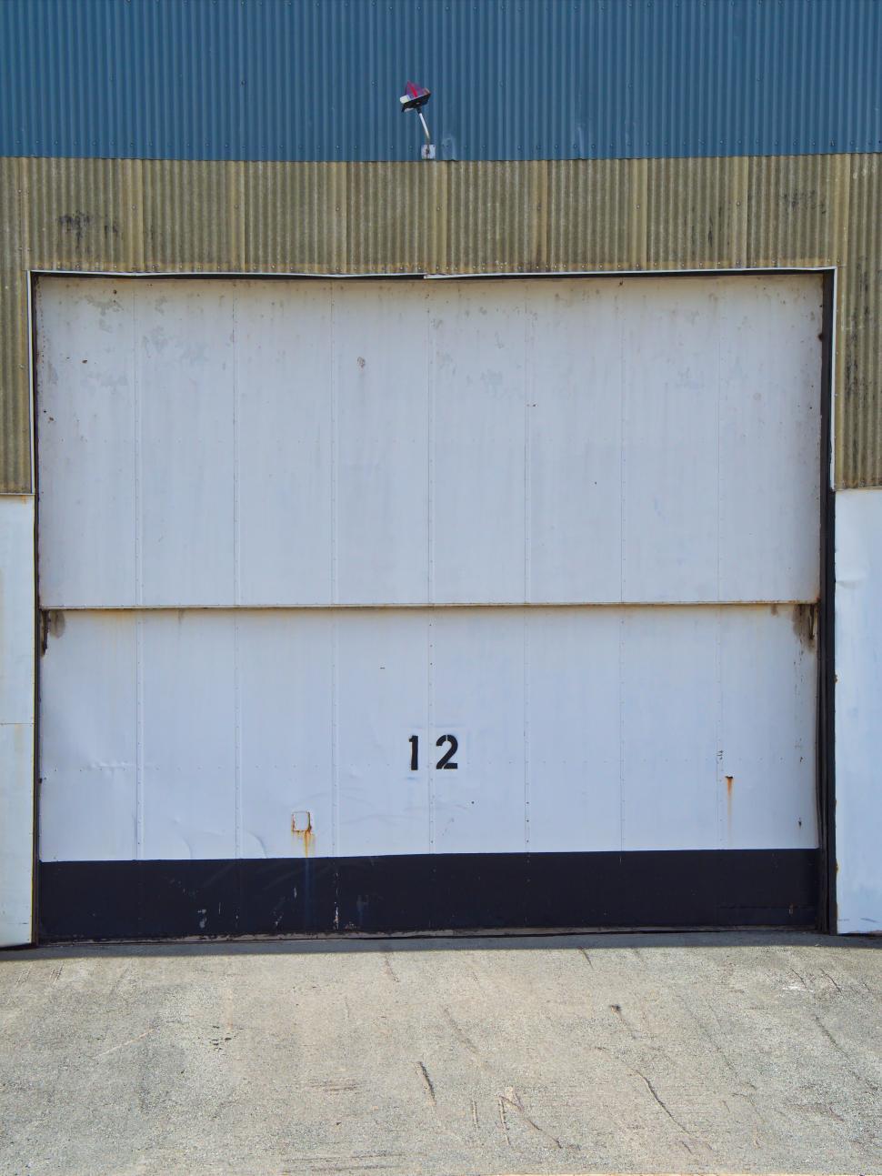 Free Image of White industrial garage door number 12 warehouse space. 