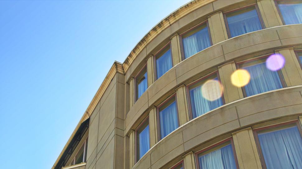 Free Image of Curved building facade with multiple windows and blue sky. 