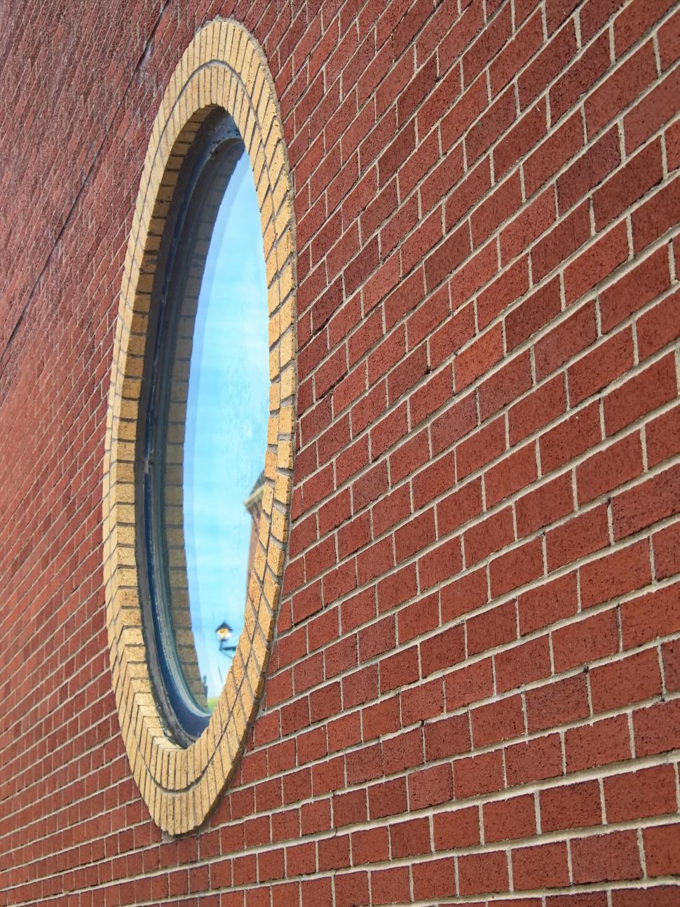 Free Image of Red brick wall with round window and brick arch frame. 
