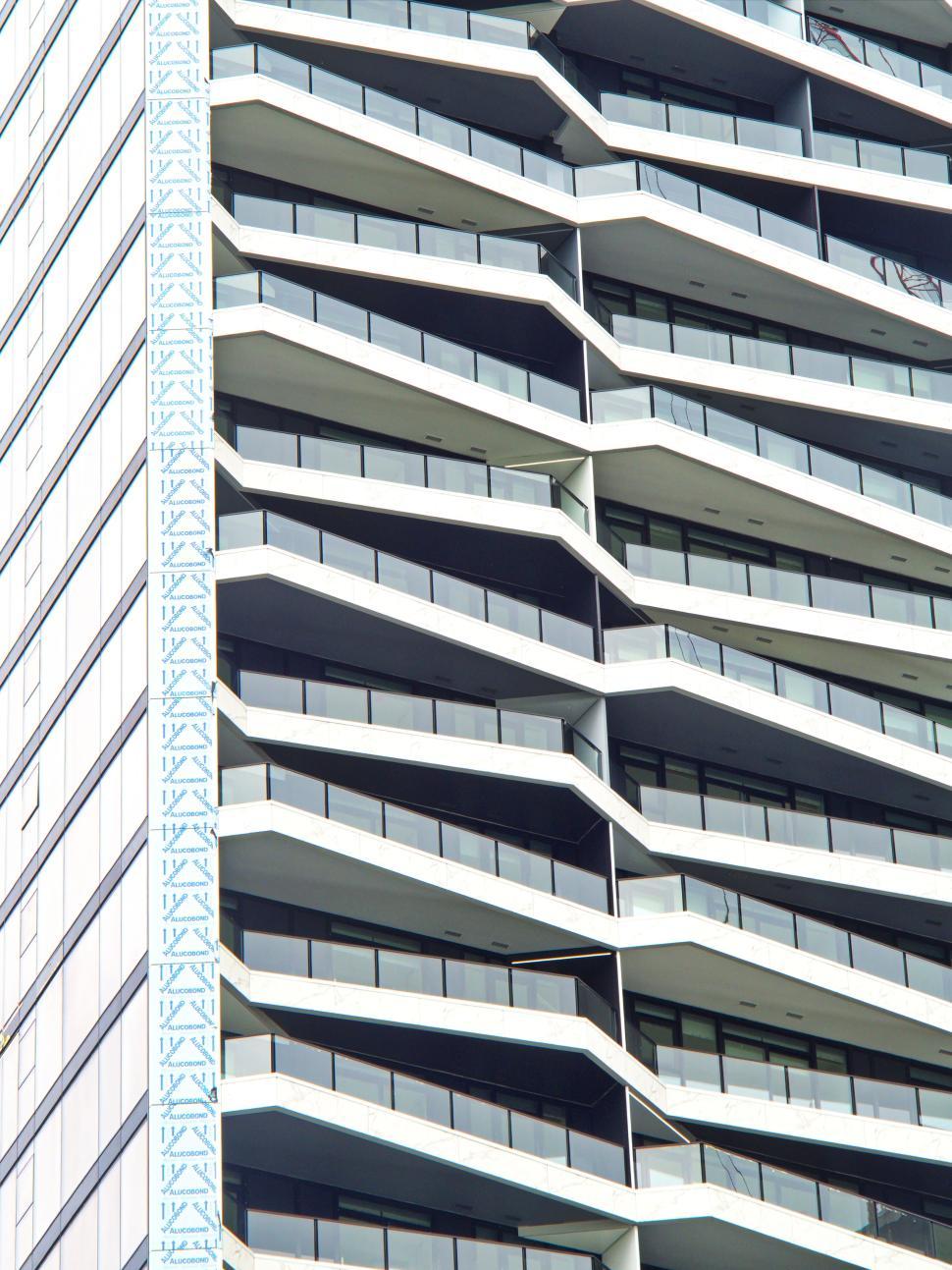 Free Image of High-rise building with zigzag balconies under blue sky. 