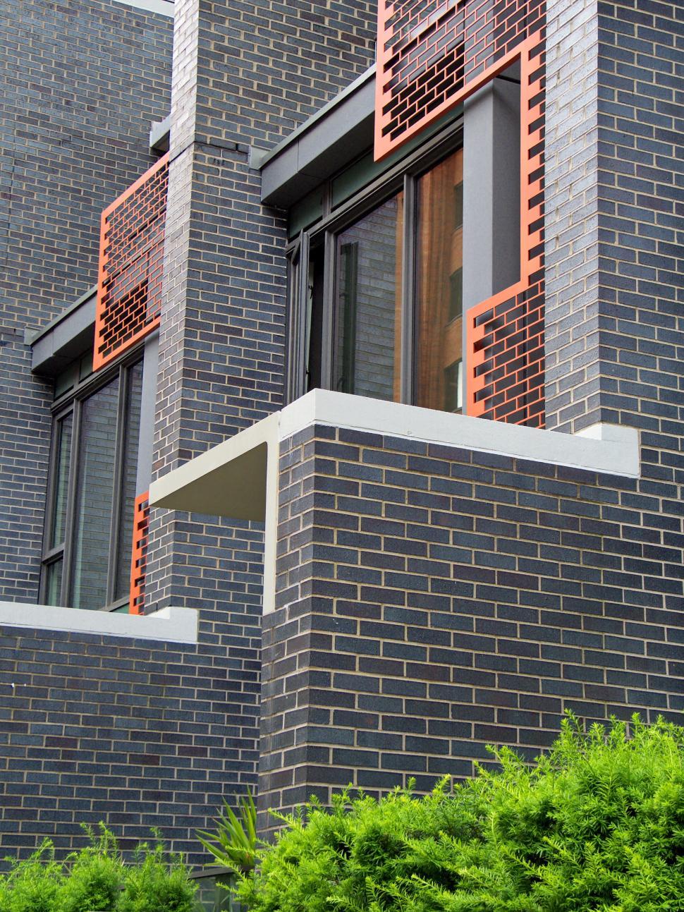 Free Image of Gray and black building with orange lattice over windows. 