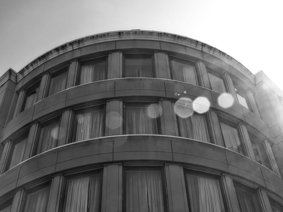 Free Image of Black and white curved building with lens flare effect 