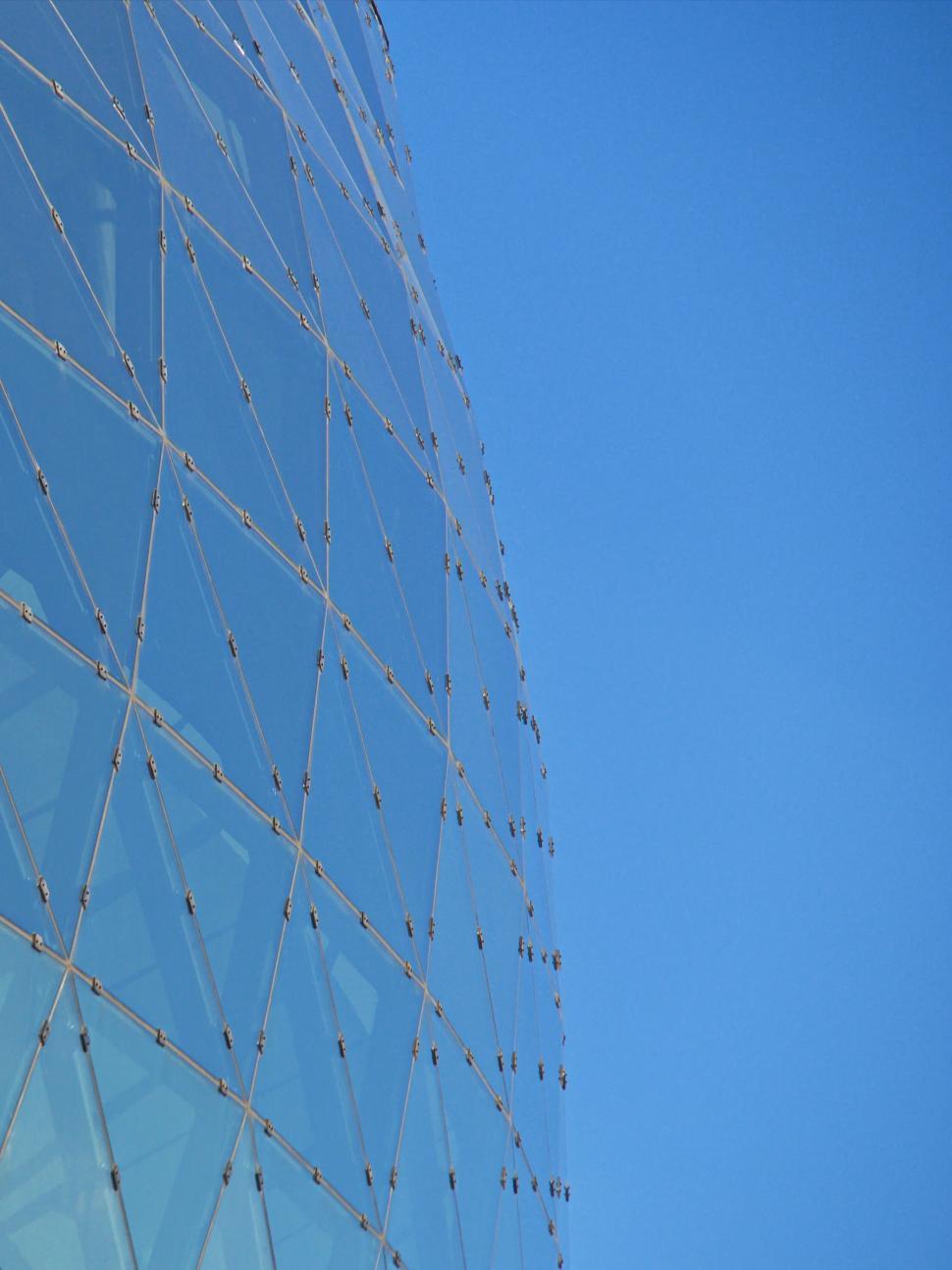 Free Image of Curved glass building with a geometric wireframe design 