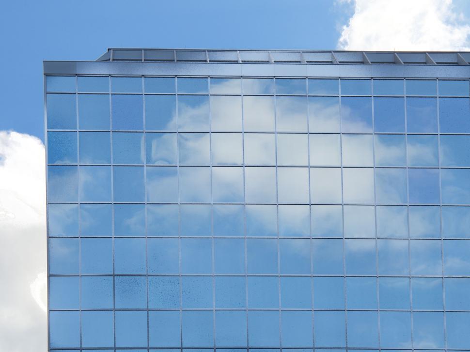Free Image of Glass building reflecting the sky with clouds, modern design 