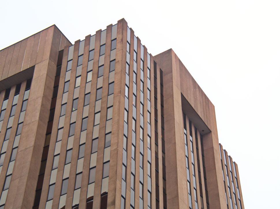 Free Image of Towering beige skyscraper with repetitive window grid design 